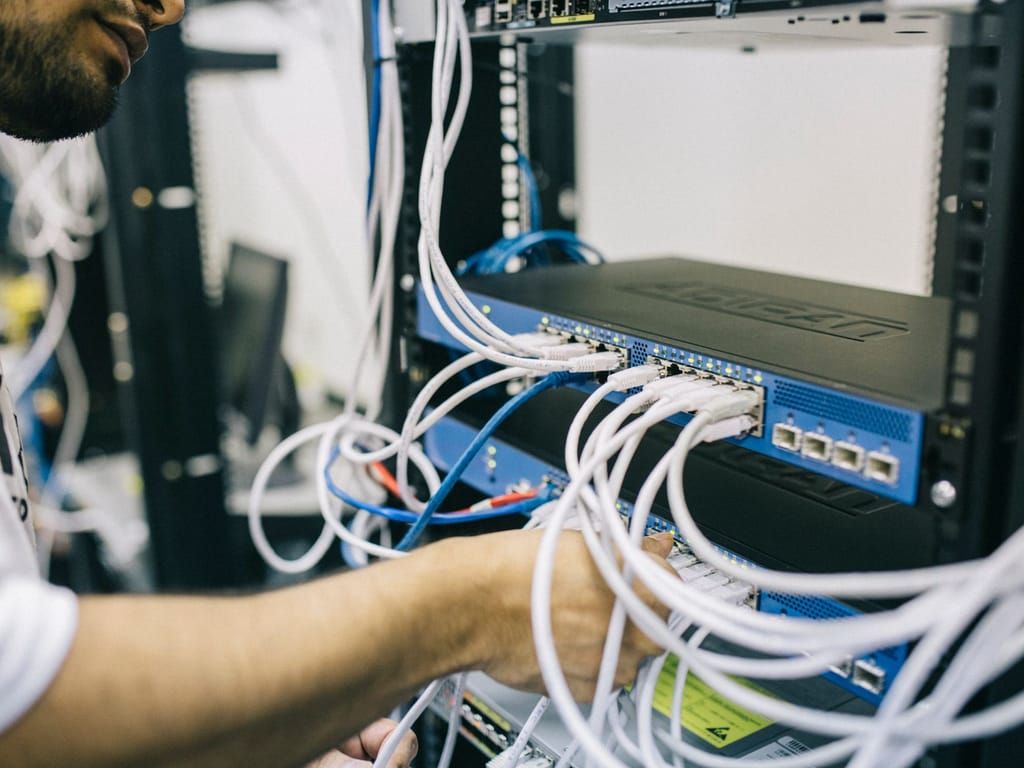 Technikerin prüft die Verkabelung an einem Switch im Serverschrank